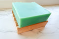 wooden soap dish with green soap on top of it on a white surface