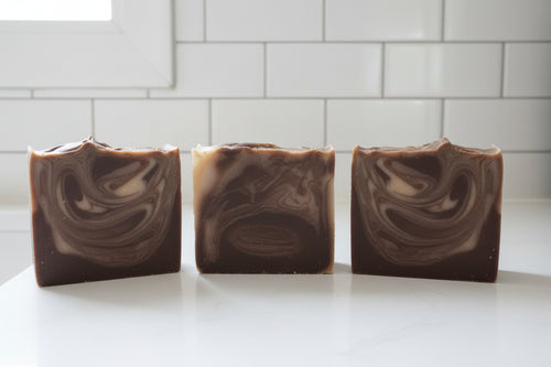 three bar of brown soap with white swirls in a white bathroom