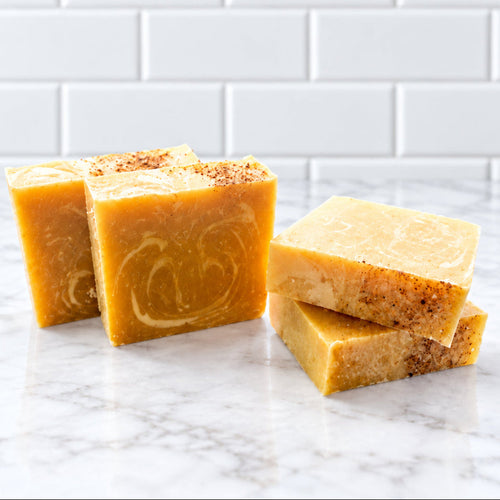 four bar soaps made with organic pumpkin puree for the orange color on top of a white counter with white tile in the background