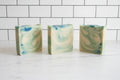 3 bar soaps with dark green, light green and white swirls on a white surface
