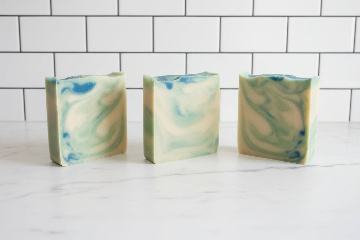 3 bar soaps with dark green, light green and white swirls on a white surface