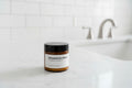 Jar of magnesium cream made with plant based ingredients on a bathroom counter with a blurred background