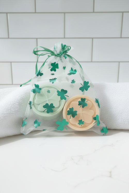 Two bath soaps with clover designs in a decorative bag.