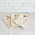 natural fiber sisal soap bag. three bags with wooden beads on a white surface