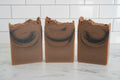 3 brown soaps with black swirls on a white surface