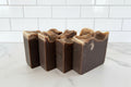 Vegan bar soap with vanilla bean scent profile and dark brown in color on a white surface