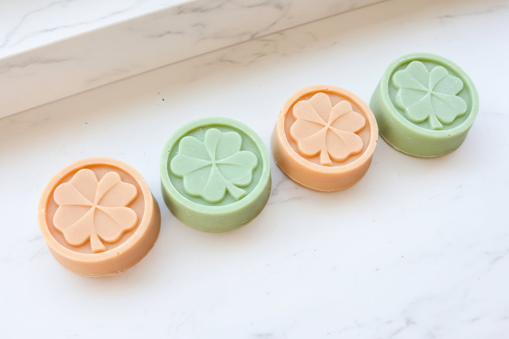 Four soaps with clover leaf designs on a white background