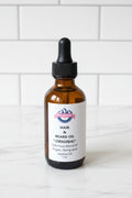 A 2oz amber glass dropper bottle of Beard & Hair Original Beard Oil with a white label, set on a white ledge next to a window with strong natural sunlight casting a shadow.
