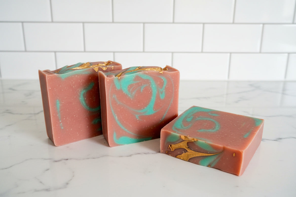 3 bar soaps with red, green and gold swirls on a white surface
