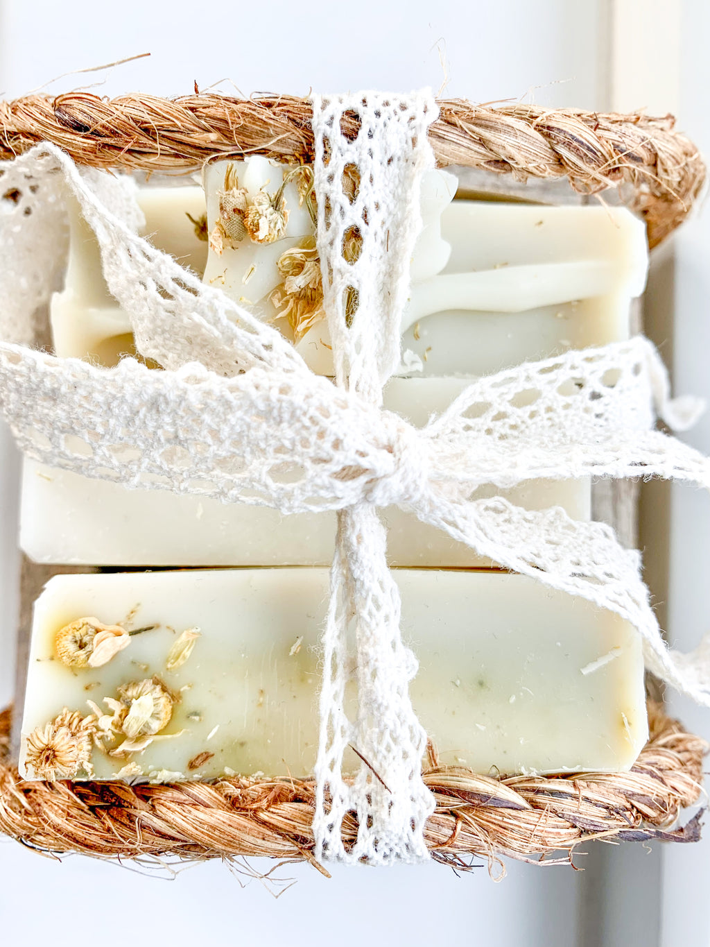 Bar of soap with natural elements and lace ribbon on a white background