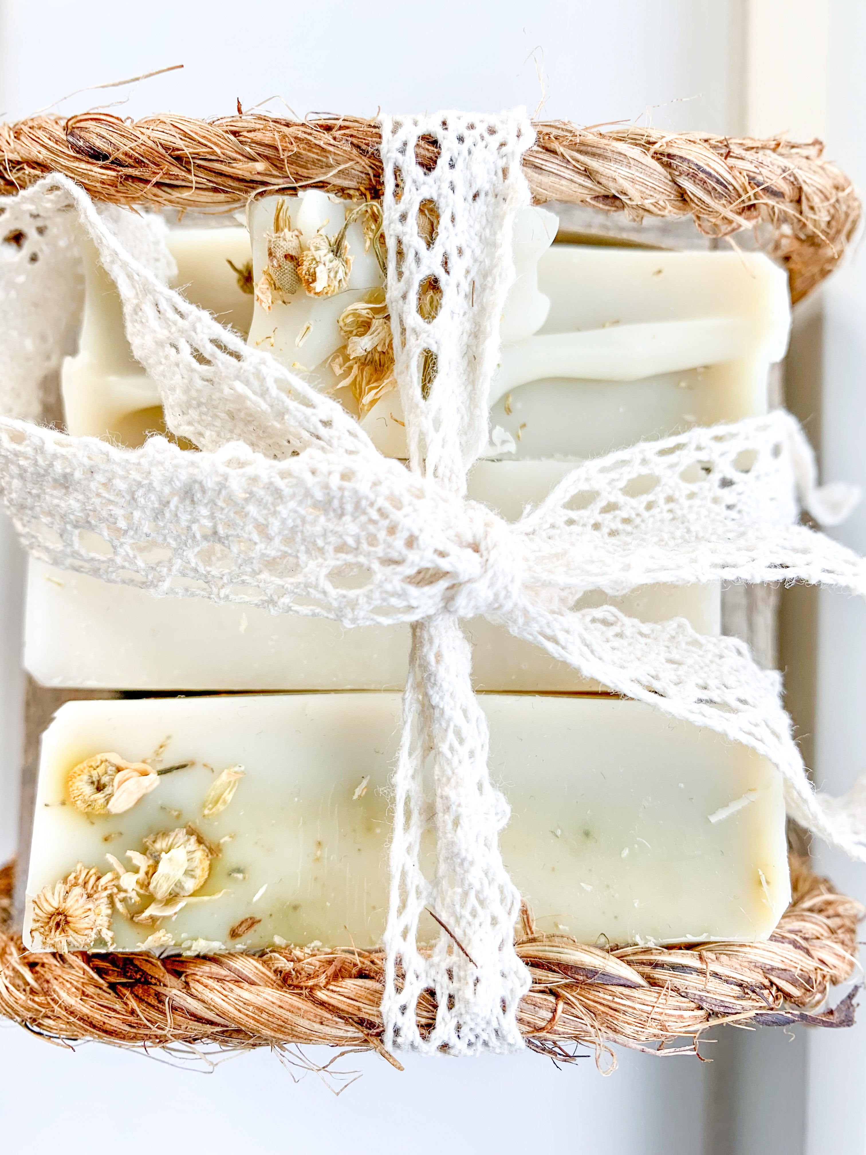 Bar of soap with natural elements and lace ribbon on a white background