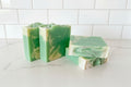 four green and white swirl bars soaps with a touch of glitter on a white surface